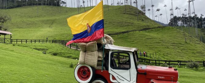Valle de Cocora - červené staré auto s kolumbijskou vlajkou a v pozadí štíhle a vysoké voskové palmy na kopci