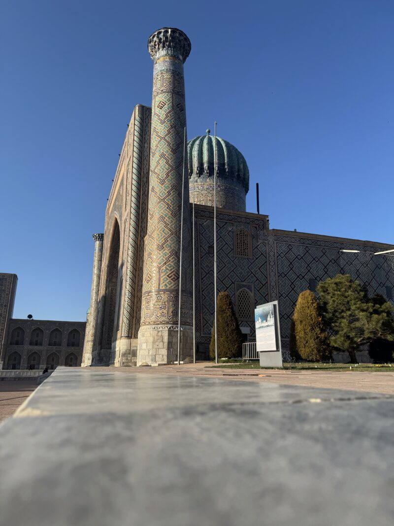 Samarkand, predná časť fotky rozmazaná zem a ostrá časť fotografie je medresa Sherdor